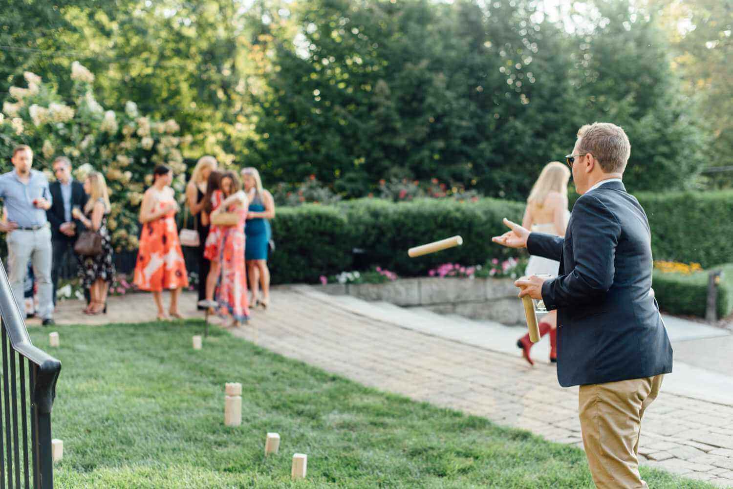 013-kate-eldar-lake-house-inn-rehearsal-dinner-philadelphia-wedding-photographer-alison-dunn-photography-photo A man in a suit is playing a game of quoits with a group of people.