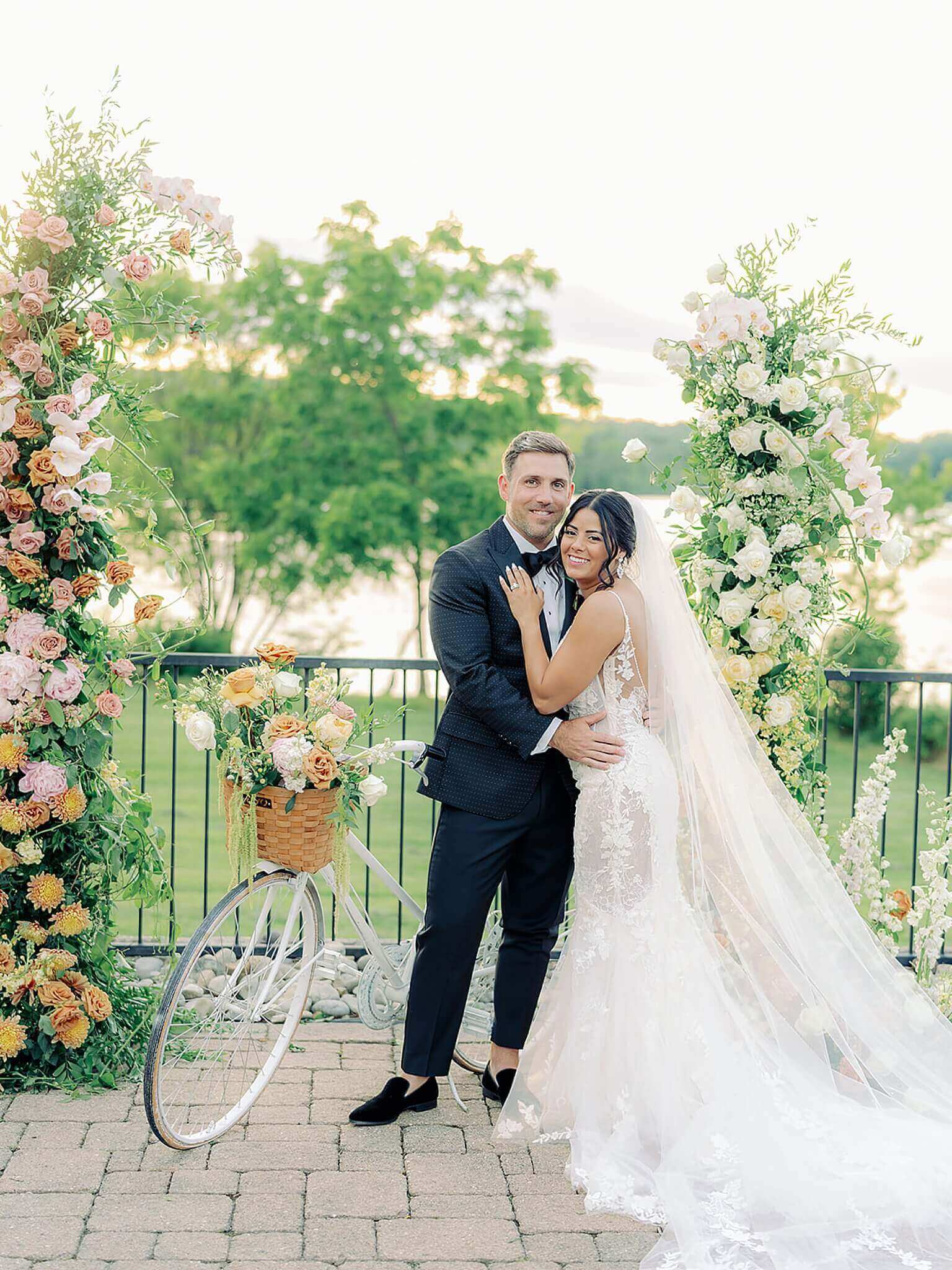 A bride and groom posing for a wedding photo in front of flowers.