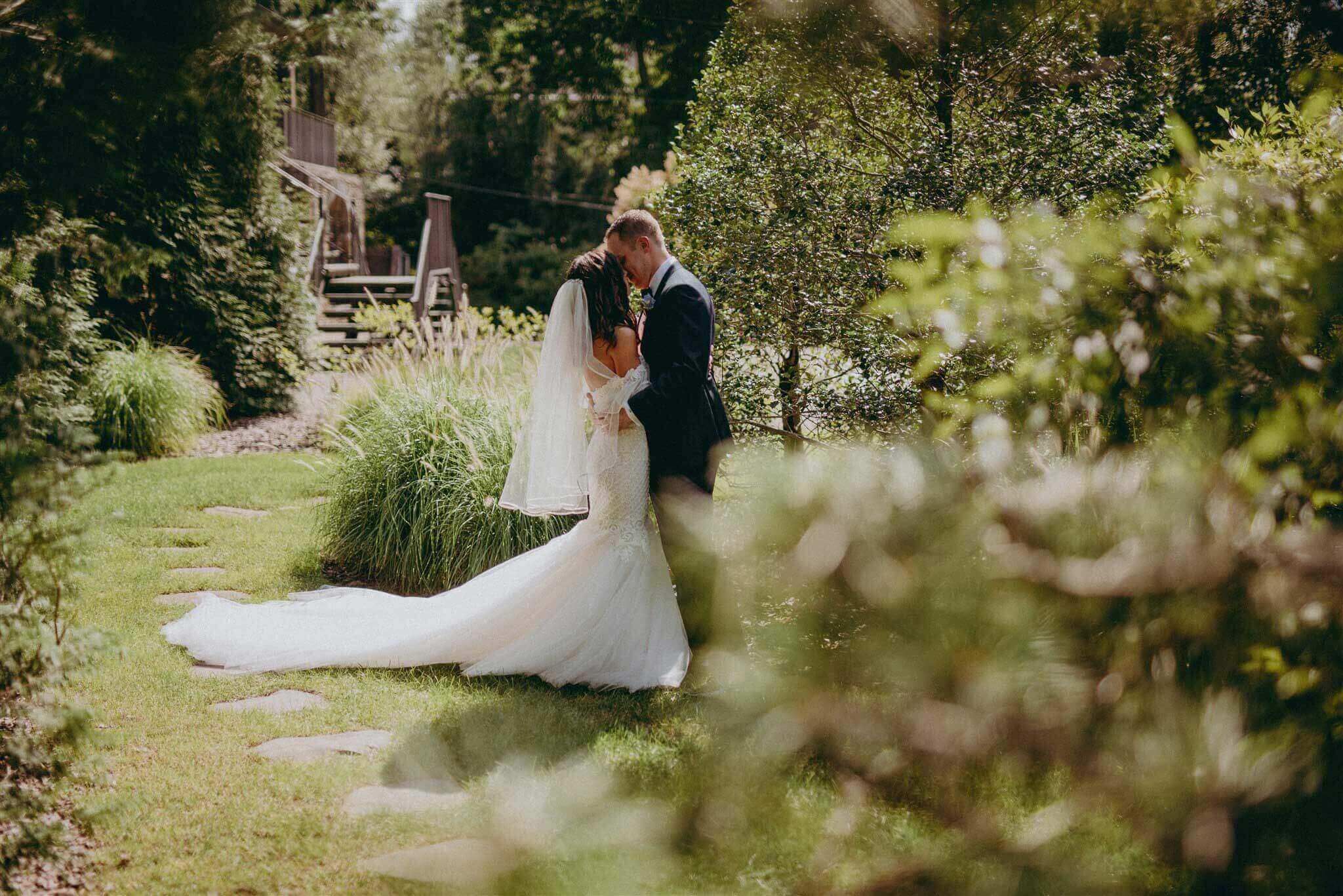 A bride and groom kissing in a garden.