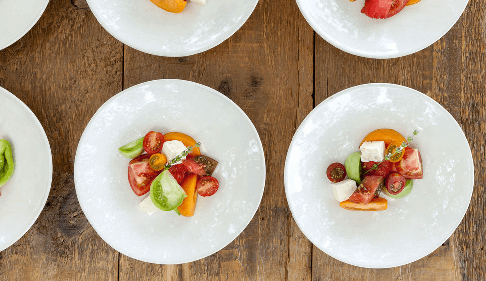 A plate of fruits and vegetables on a wooden table.