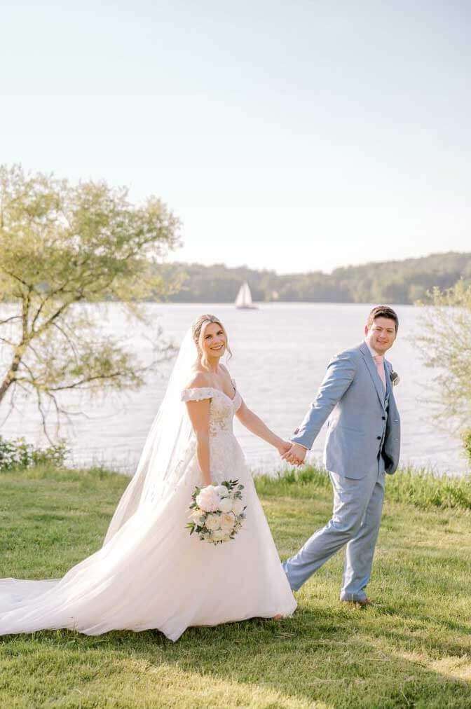 A-Spring-Lake-House-Inn-Wedding-by-Lytle-Photography-Company_0084-1-686×1024 A bride and groom holding hands in front of a lake, celebrating with one of our exclusive wedding packages.