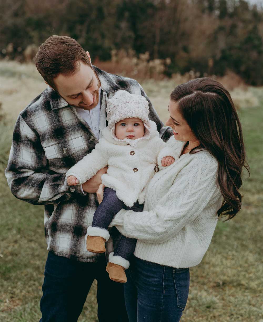 Annelise-Jayme-Family-Session-8 A family holding a baby in a field.