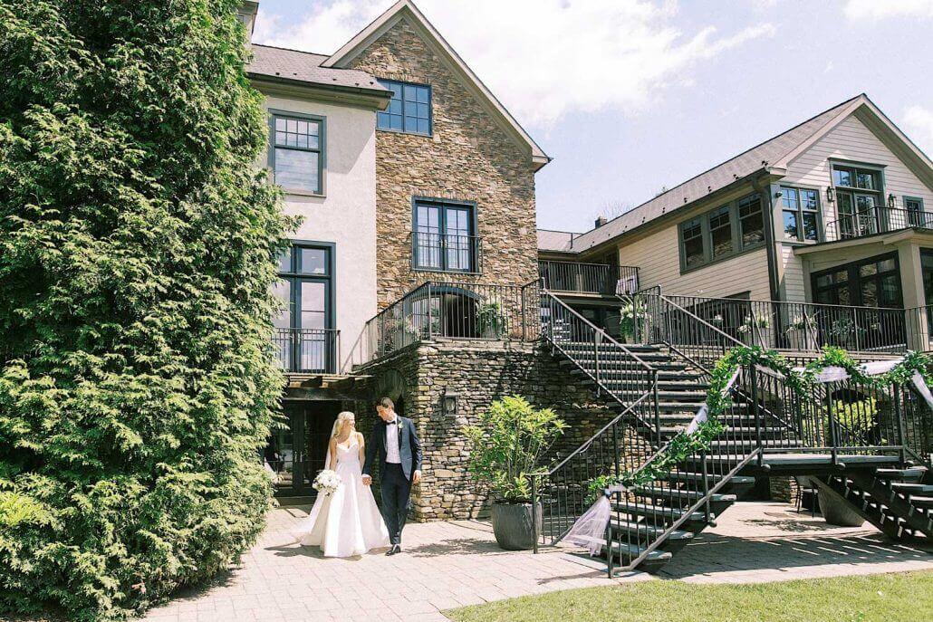 A bride and groom standing in front of a house.