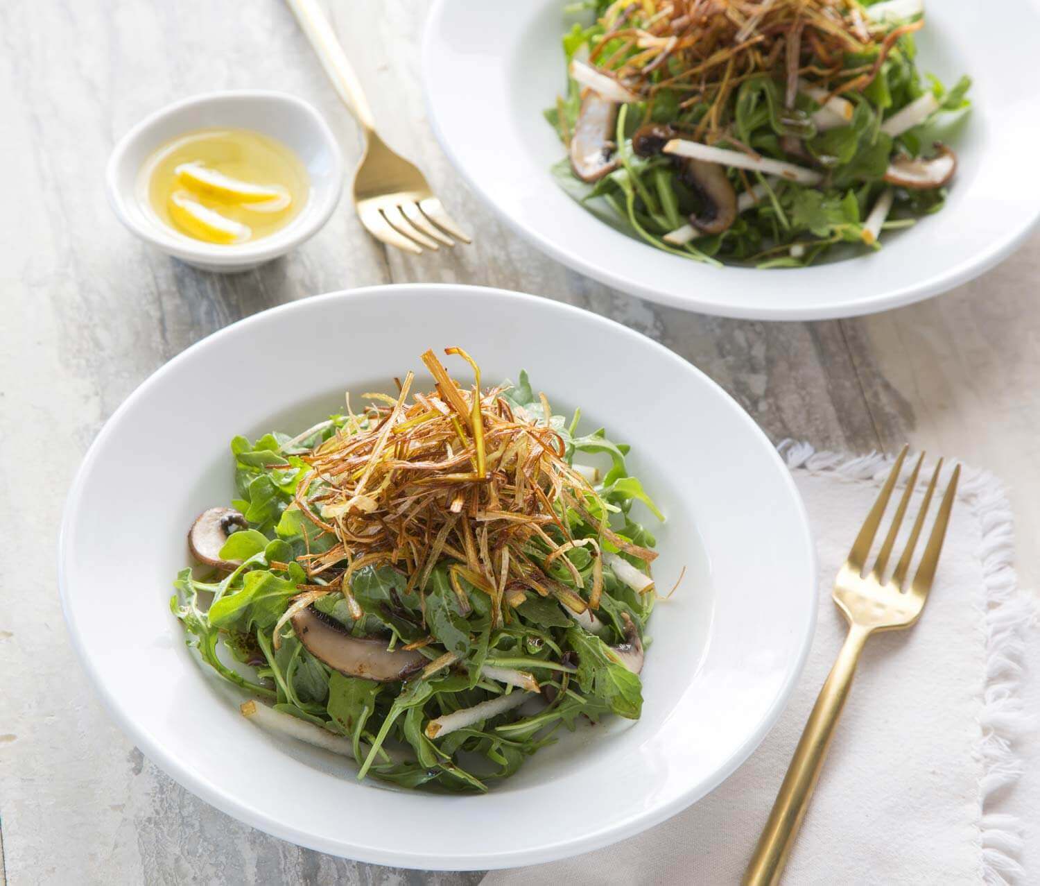 Two bowls of salad with mushrooms and a fork.